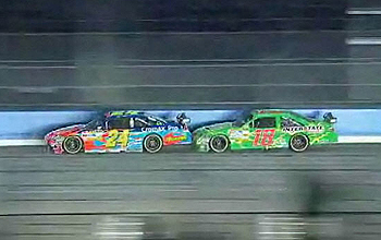 One race car follwoing closely behind another race car on the track