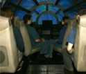 Photo of visitors seated at a full-size replica of the Millennium Falcon cockpit.