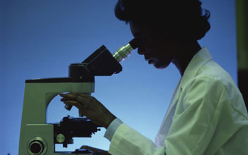 a researcher peering through a microscope.