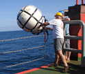 Photo of researcher Jamie Austin deploying a sound source and wave recorder.