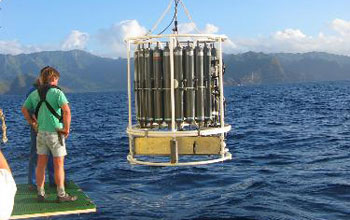 Photo of a researcher on a research vessel watching seawater sampling equipment.