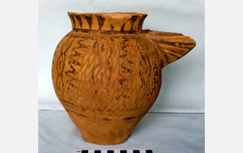 Photo of a strainer spouted pitcher painted and impressed in a pattern of connected ovals.