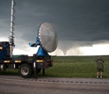 Scientist with Vortex-2 equipment on the side of the road looking at a twister