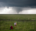 Researchers in the field studying a tornado in the distance.