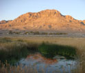 Photo of dessert, mountains, houses and a small body of water.