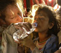 Photo of a US woman soldier giving water to drink to a girl.