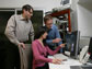 Three professors in a lab looking at monitor