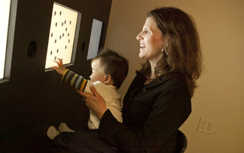 woman holding a baby touching a screen