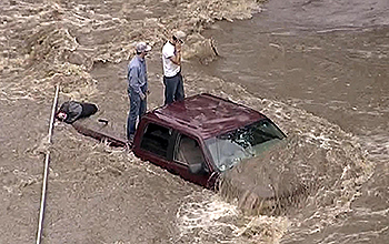 Two people on truck bed amid rising water