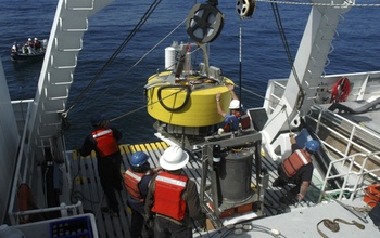 men on research vessel working with a floatation buoy