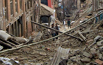 A few people walk amid rubble from collapsed buildings