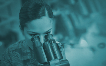 A woman in Air Force uniform looks through a microscope.
