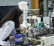 A researcher interacts with a table-top sized metal machine