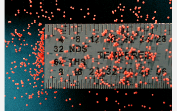 Healing agent containing microcapsules used in self-healing polymers, with ruler to compare size