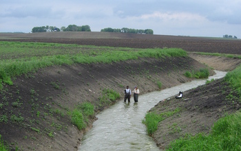 Scientists measure water velocity and collect samples in an agricultural ditch.
