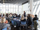 Conference room at Northeastern Illinois University filled with researchers sitting at tables listening to a lecture