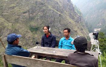 Photo showing two researchers interviewing locals in the mountains