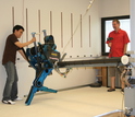 Two people and a robot with lateral support boom.