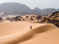 Man walking up sand dune in the Sahara Desert.