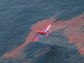 An aircraft applies dispersants over a slick of sunlight-weathered oil in the waters of the Gulf of Mexico.