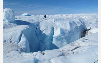Researcher stands on edge of one of four moulins (drainage holes) found at bottom of a glacial lake