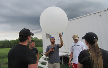 A research team of four men and one woman prepare to launch a weather balloon.
