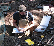 Patch of ground in the Pacific Northwest, with scientist making soil analyses.