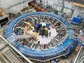 The Muon g-2 ring sits in its detector hall amidst electronic racks, the muon beamline and other equipment. The experiment operates at negative 450 degrees Fahrenheit.