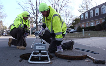 Two men and equipment at a sewer opening