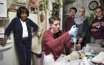 researchers test water in a kitchen while the resident is watching