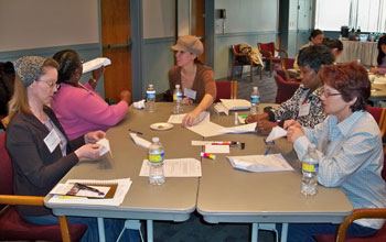 Photo of women entrepreneurs seated around a table doing team-building exercises.