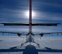 Photo of a Twin Otter aircraft silhouetted by the sun.