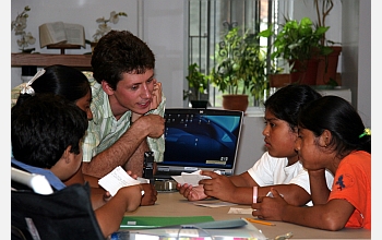 Teacher and students around a computer monitor.