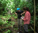 Photo of a scientist collecting a soil sample using an auger and another scientist taking notes.