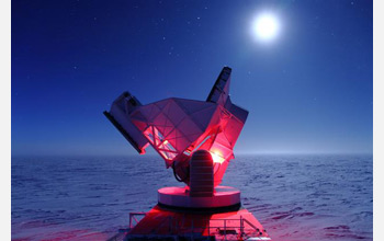 Photo of the South Pole Telescope illuminated by red lights.