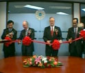 Four officials prepare to cut a red ribbon at the ribbon-cutting ceremony