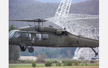 Photo of a Blackhawk helicopter lifting off in front of the Robert C. Byrd Green Bank Telescope.