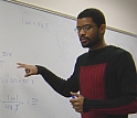 Student at white board works with other student on math problem