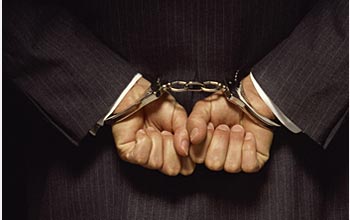 Photo of a man's hands cuffed behind his back.