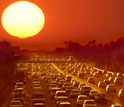 Photo of sun shining over cars in busy traffic on a highway