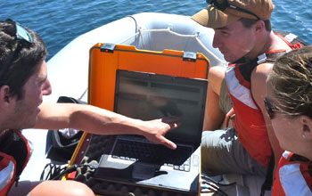 Student researchers in a boat use acoustic imaging to select a lake site