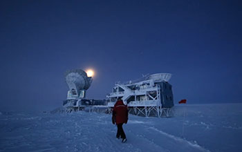 Man walking toward telescope at the South Pole.