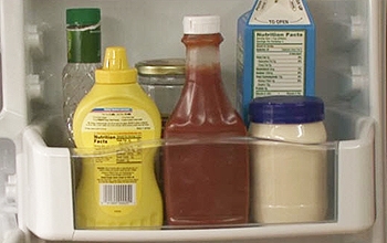 Containers of condiments on a refrigerator shelf