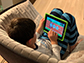 little boy sitting on a sofa playing with a tablet