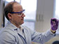 professor Andrew Whelton holds up a water sample from a building faucet