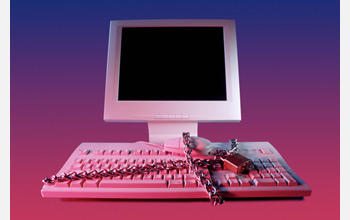 Photo of a computer locked with a chain and pad lock.