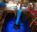 Photo of a recovery tool for sea-floor equipment rising through the ship's moonpool.