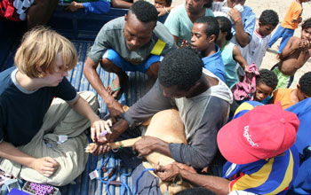 Photo of a dog's blood being take in the back of a pick-up truck mobbed by interested Papuans.