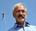 Photo of Michael Caramanis under a small wind generator.