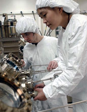 Photo of Ting Liu explaining the use of molecular beam epitaxy to undergraduate Kirk Pirlo.